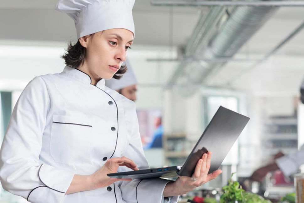 Chef on a laptop in restaurant kitchen